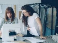 Two women working on clothes in a studio.